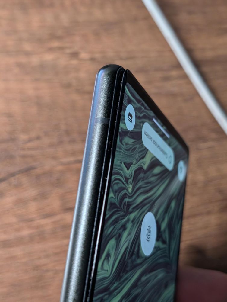 The side view of a black smartphone with the screen slightly detached from the body. A portion of the phone's lock screen wallpaper is visible, along with a fingerprint icon.