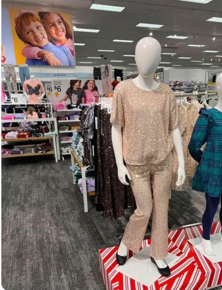 A mannequin at the Target Kids section consisting of a loose, blousy sequined top and matching sequined slacks and ballet flats. The blouse and slacks are a very pale, dusty pink under the sequins.