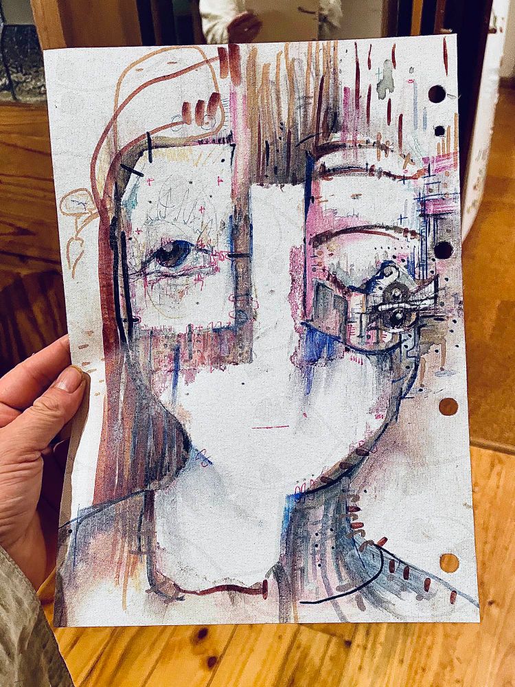 A hand hold a drawing of a femme face with brown hair and her two eyes pushed apart and in detailed boxes
The rest of the face is bare except for a thin small line of a mouth 