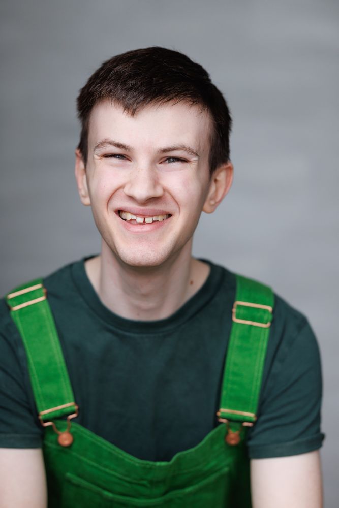 Max Bayford - Performer, Writer, Theatre-Maker

A headshot of Max fully smiling, wearing a dark green t-shirt and lighter green dungarees. 