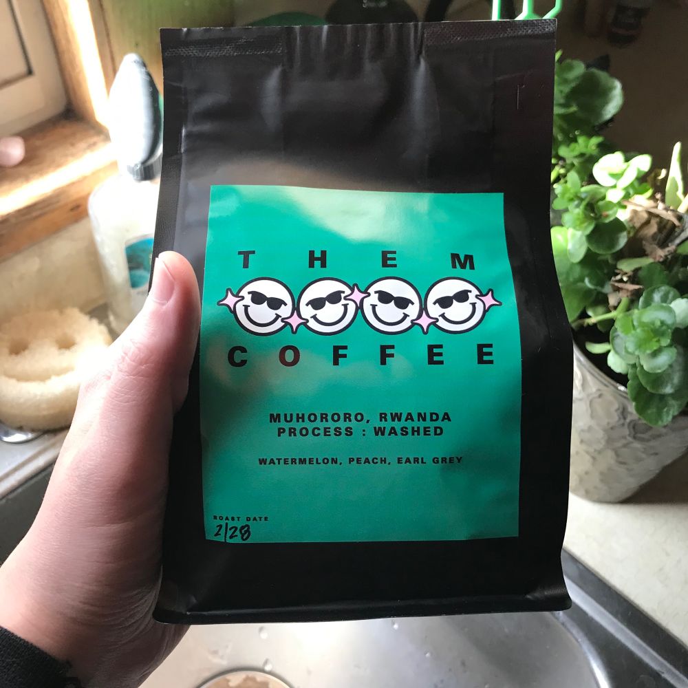 a sealed black and green bag of whole Muhororo coffee beans from Them Coffee 