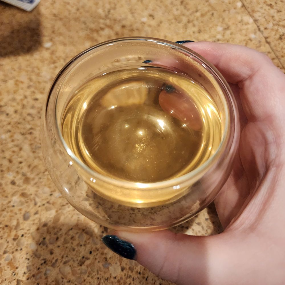 A small glass cup full of tea.