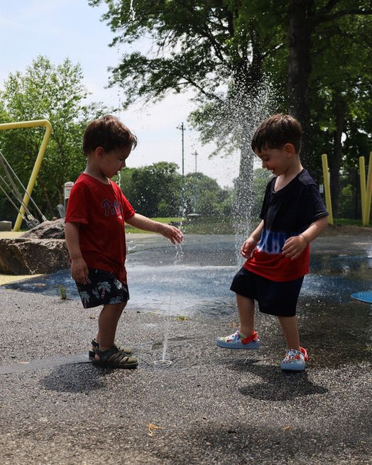 Two children play in splash pad at City of Boston park.
