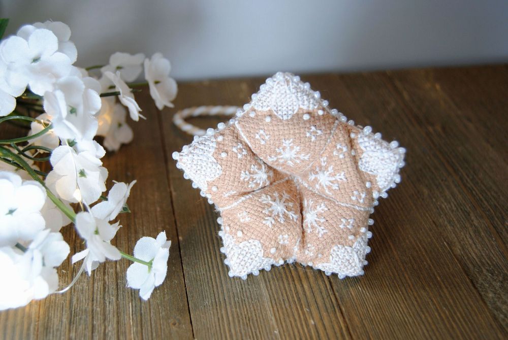 The bottom of a cross stitched 3d bell shape with white stitching on gingerbread aida.