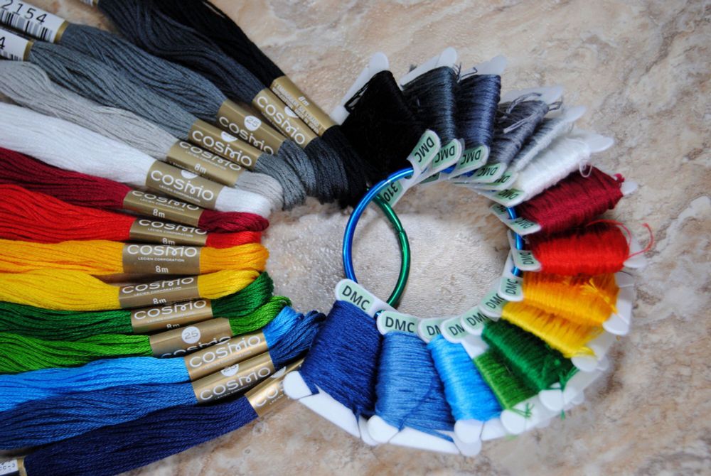 Cross stitch / embroidery thread in a nearly rainbow palette of colors. 
Two different brands, both skeins of Lecien Cosmo thread as well as bobbins of DMC brand thread.