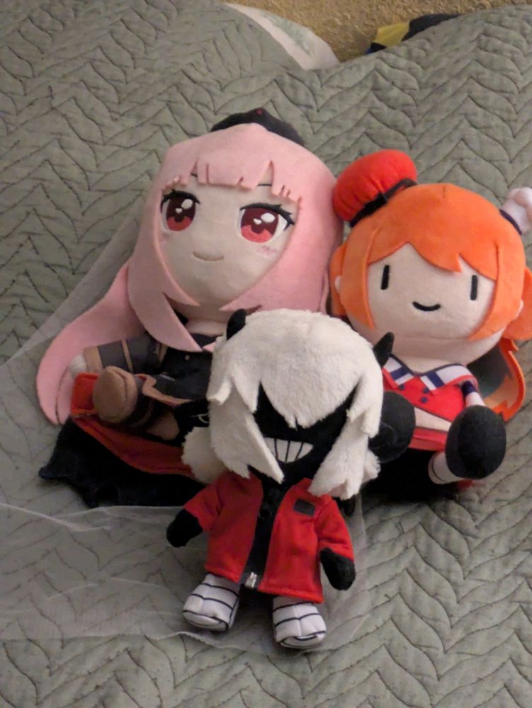 a fanmade Mori Calliope plush lying next to a Smol Kiara plush with Demondice plush positioned like they're a family unit 
