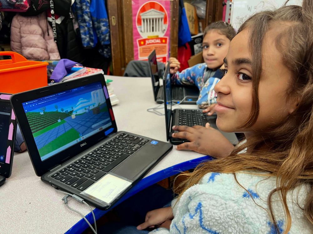 Girl, smiling next to a computer