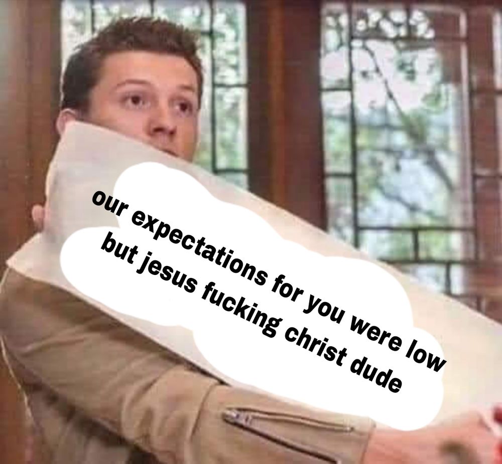 A picture of Tom Holland holding a big sign that reads "our expectations for you were low but jesus fucking christ dude"