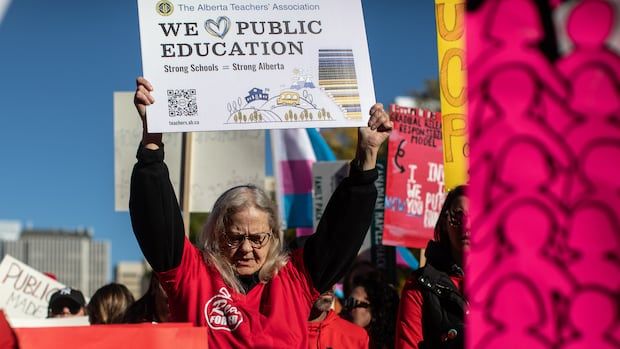 A woman holds a sign that says We Love Public Education at a rally. 