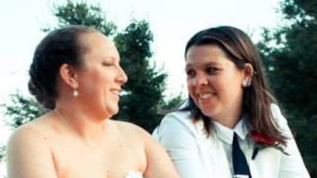 two women in wedding attire smiling at each other