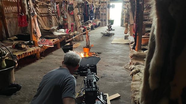 Cameraman filming in replica Longhouse.