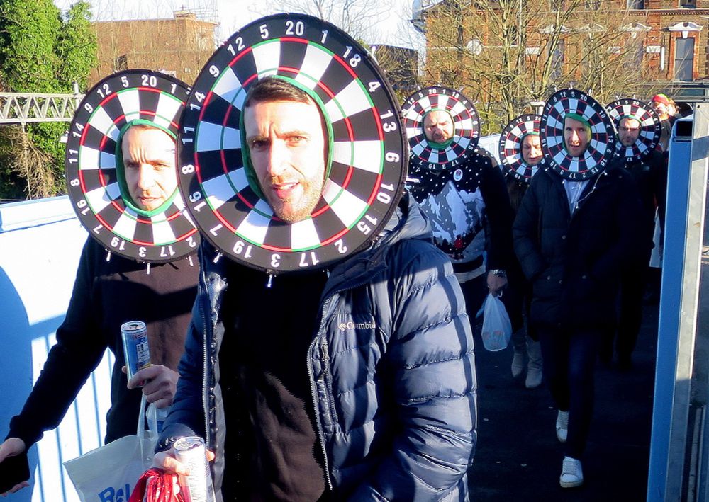 Darts fans on their way to the World Darts Championships
at Alexandra Palace in London,
each with their face framed
by a convincingly mocked-up darts board. 
Don't throw! 
Photo:  Hugh Sykes. 