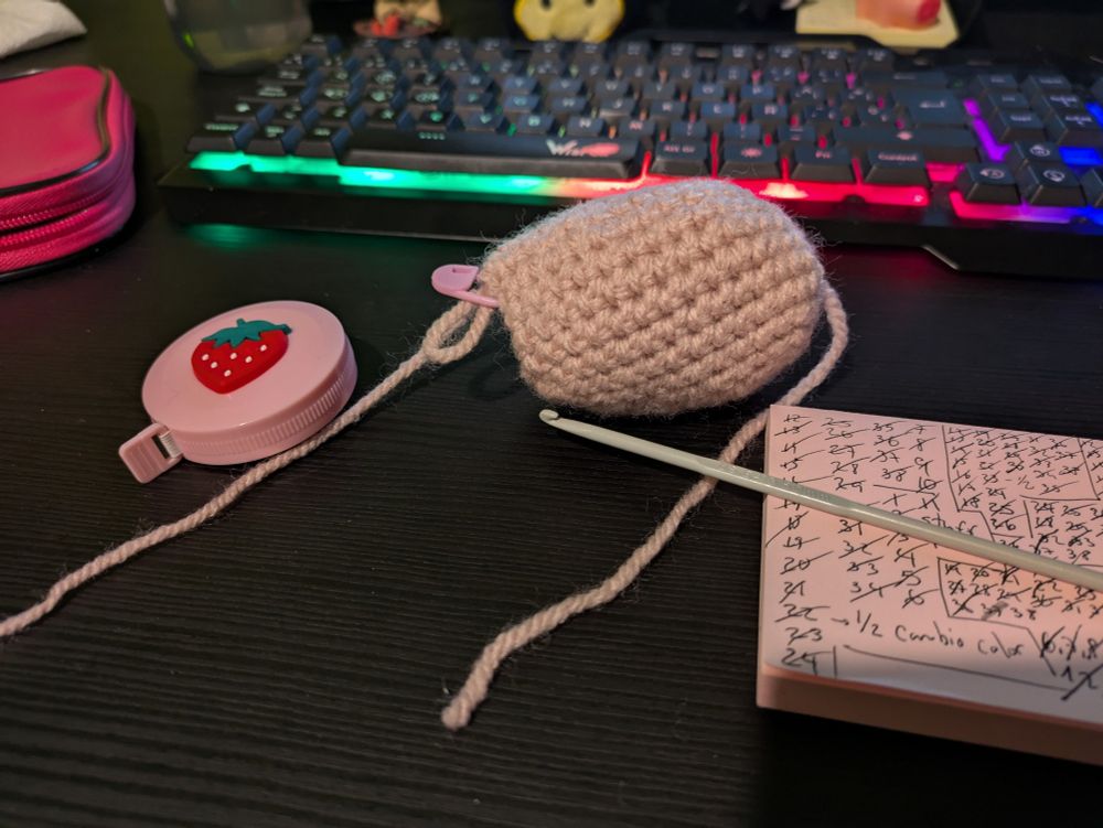 El cuerpo rosa hecho de ganchillo de un cerdito, con un metro y un ganchillo al lado.