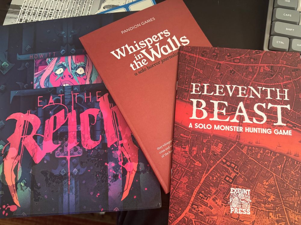 Instruction books for Eat the Reich, Whispers in the Walls, and Eleventh Beast ttrpgs