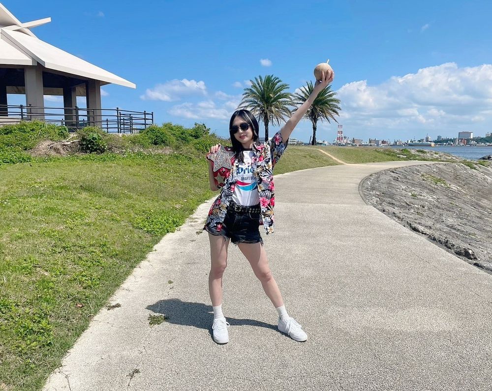 Professional wrestler Saya Kamitani poses in a Hawaiian shirt & sunglasses, holding a coconut in Okinawa 