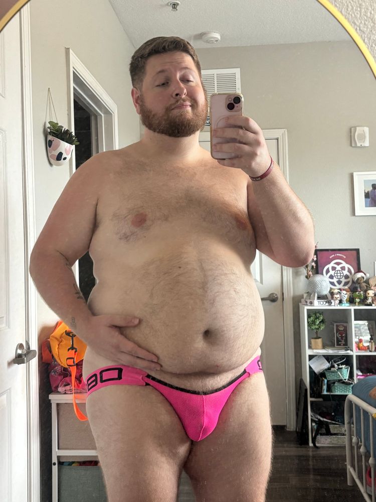 Standing in front of my mirror showing off my belly and my new neon pink jockstrap. The jock rides low in the front showing off my pubes. 