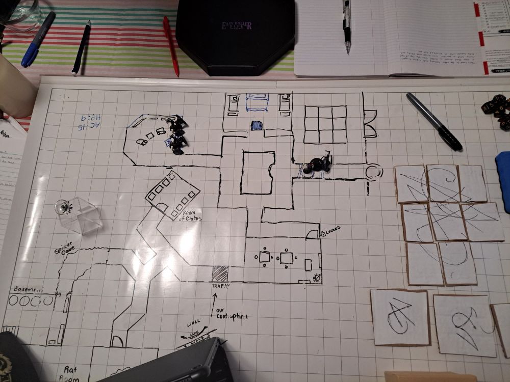 A picture of a wet erase gridded mat, with a drawing of a dungeon on it. It has winding corridors. Leadong from a basment to a small cave of spiders to an intersection that leads to a room full of giant rats to abandoned spider filled storage rooms leading past a trap to a kitchen dinning hallwoth a hobgoblin that leads to an intersection that leads a shabby library with more hobgoblins, then a bedroom then finally a a trapped halway that leads to a puzzle room and the unexplored boss room past it. 

There also paper and pens scattered about as well as the cut out for the puzzle the players had to solve. It was a slide to align up type puzzle.