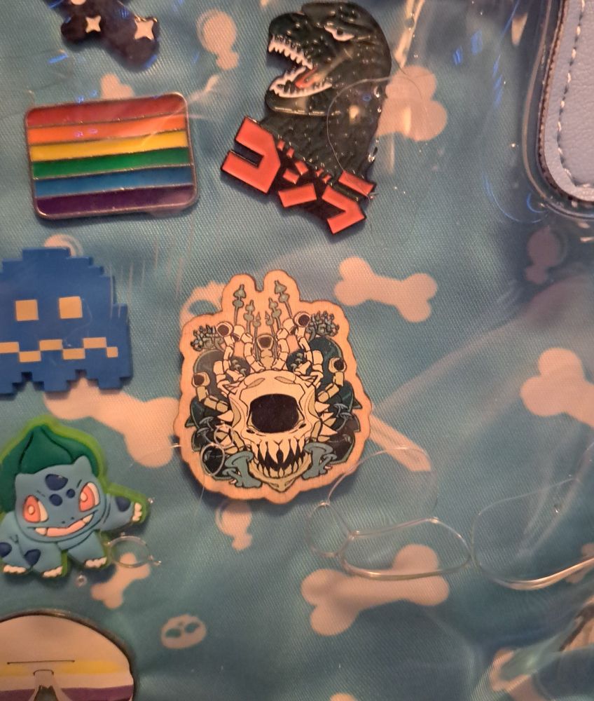 The wooden pin showing a skeletal beholder with mushrooms growing around it but closer up 