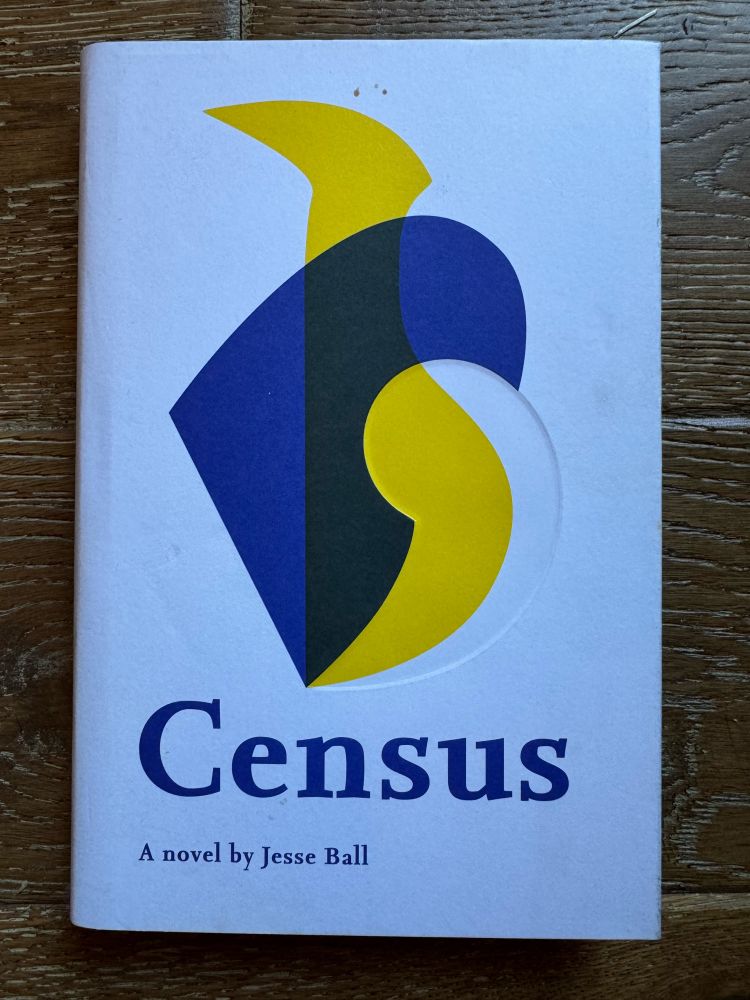 A hardback book on a wooden floor. The book is Census by Jesse Ball