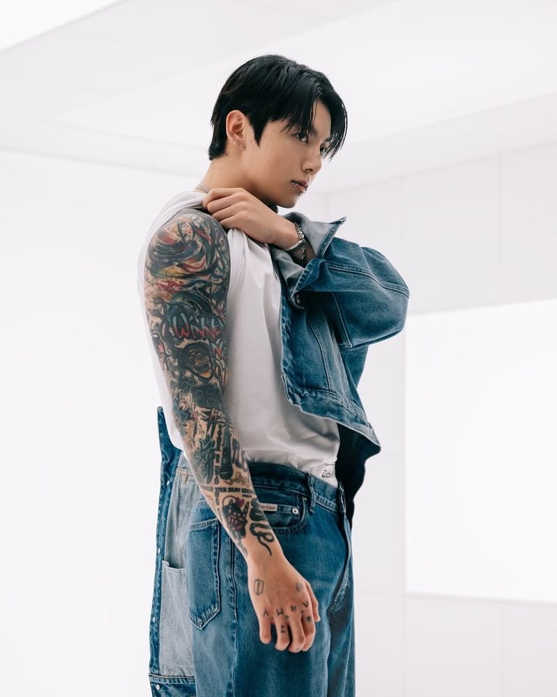 Calvin klein 2025 jk showing his full tattoo sleeve in a white room wearing a Canadian Tuxedo