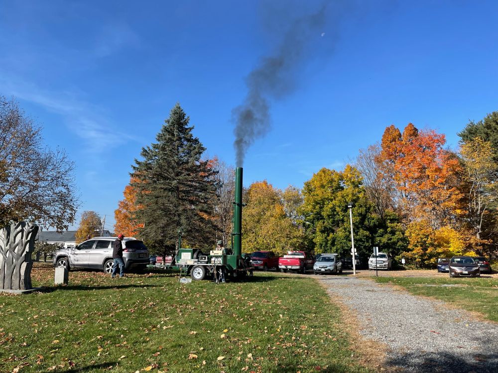 A plume of black smoke coming out of a smoke stack attached to a car’s trailer