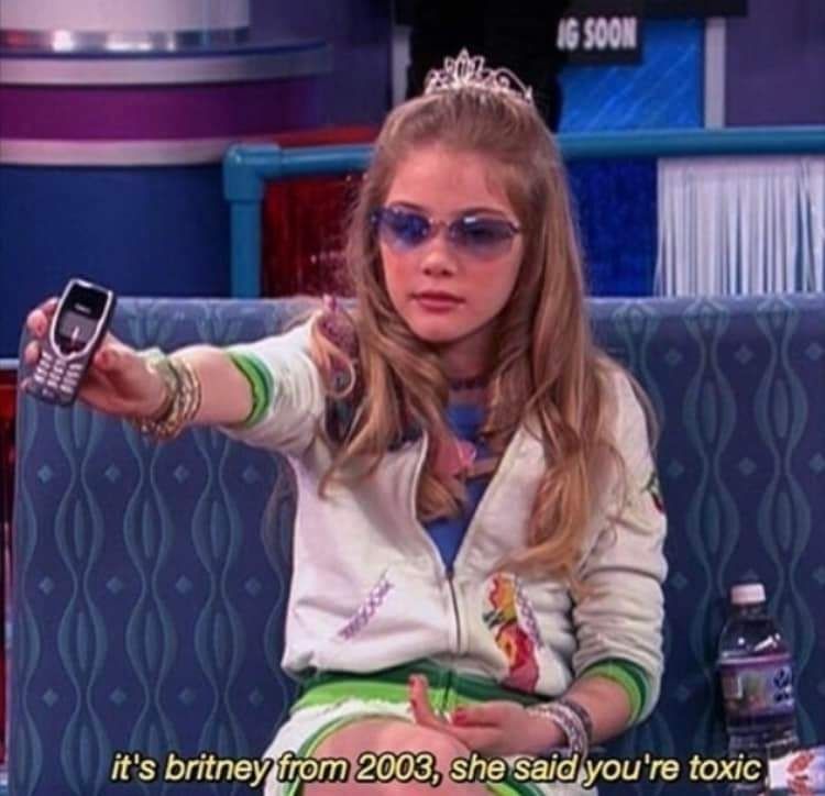 A girl holding an old T-9 cell phone out toward the reader saying "it's Britney from 2003, she said you're toxic."