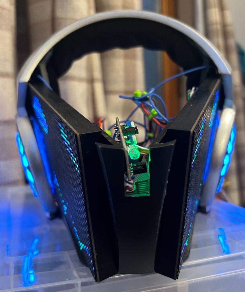 Extreme close shot of a protogen head without visor or fur attached. Hint that panels eyes glow blue, can see raw electronics in middle gap.