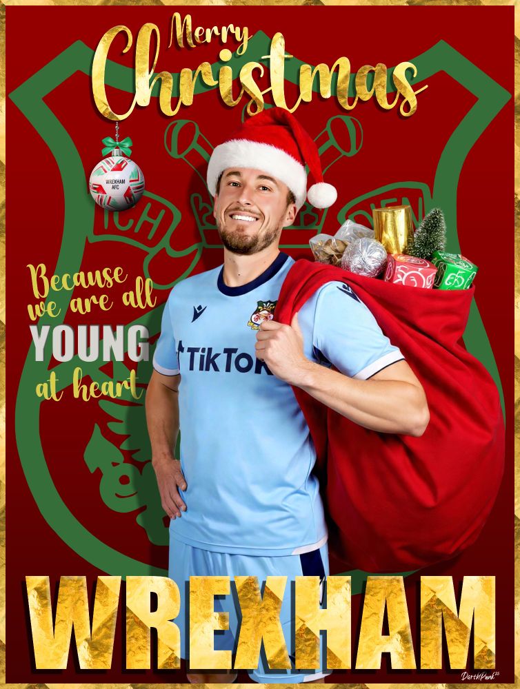 The card has a festive, bold design dominated by bright reds, greens, and golds. In the centre stands a smiling Luke Young wearing a light blue Wrexham AFC kit. He also wears a red Santa hat tipped with white fluffy trim.

He is holding a large red Santa-style gift sack slung over his shoulder. The sack is overflowing with colourful presents — shiny silver baubles, gold-wrapped gifts, and green and red boxes.

Behind him, taking up most of the background, is the Wrexham AFC club crest, shown in dark green on a deep red backdrop. The edges of the card have a shiny golden border.

Across the top, in big glittering gold script, the text reads:

“Merry Christmas”

On the left side of the player, elegant golden lettering says:

“Because we are all YOUNG at heart!”
(The word “YOUNG” is especially large and decorated.)

Near the top left hangs a Christmas bauble painted with red and white stripes and the Wrexham badge.

At the bottom of the card, in huge textured gold letters, is the word:

“WREXHAM”

The overall feel is warm, cheerful, and festive — blending Christmas imagery with football pride.