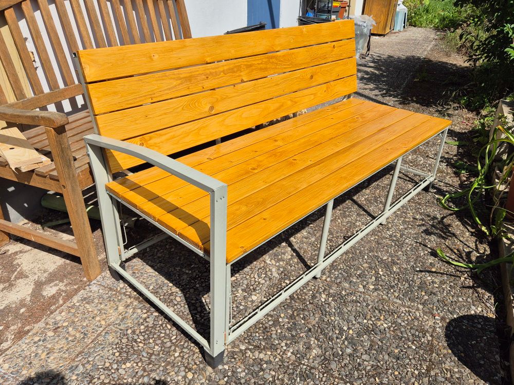 Graues Bankgestell aus Metall, mit Kiefernbrettern beplankt