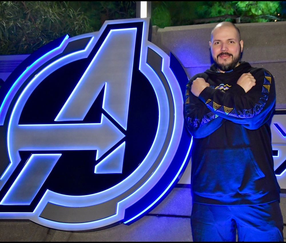 Avengers logo with me ruining it standing next To it 