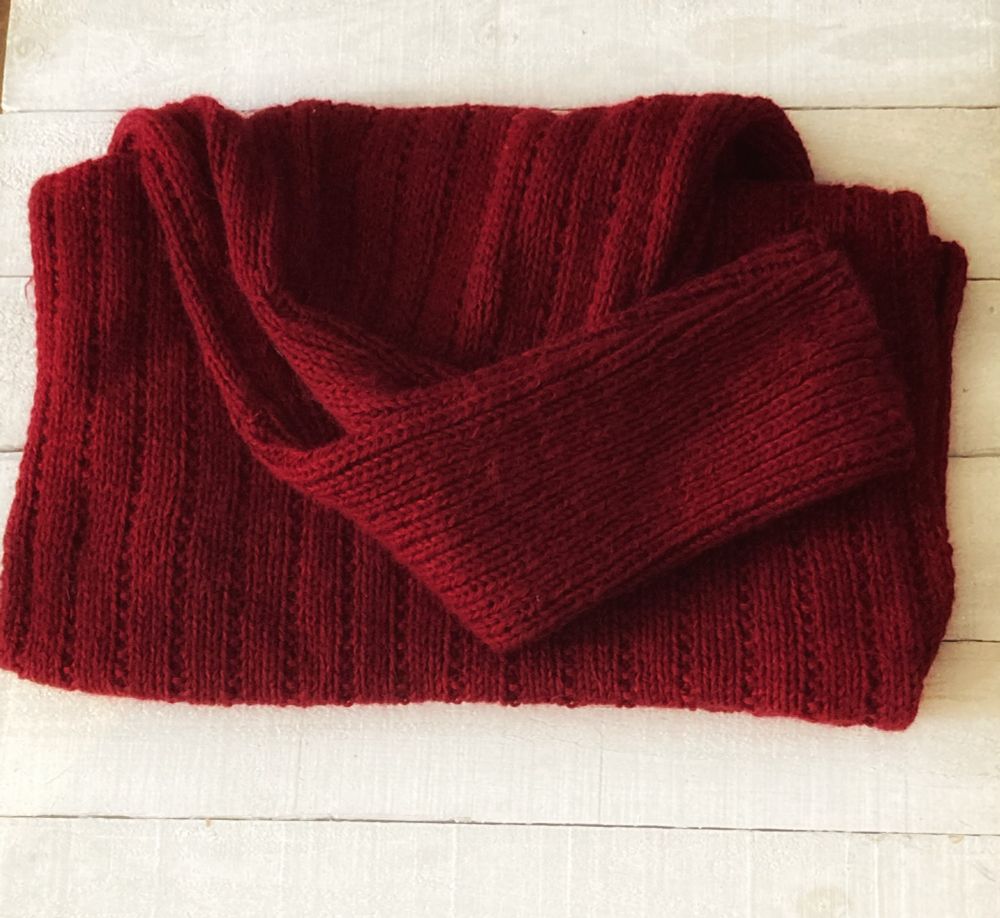 completed merlot coloured knitted sleeved wrap on a white wooden background