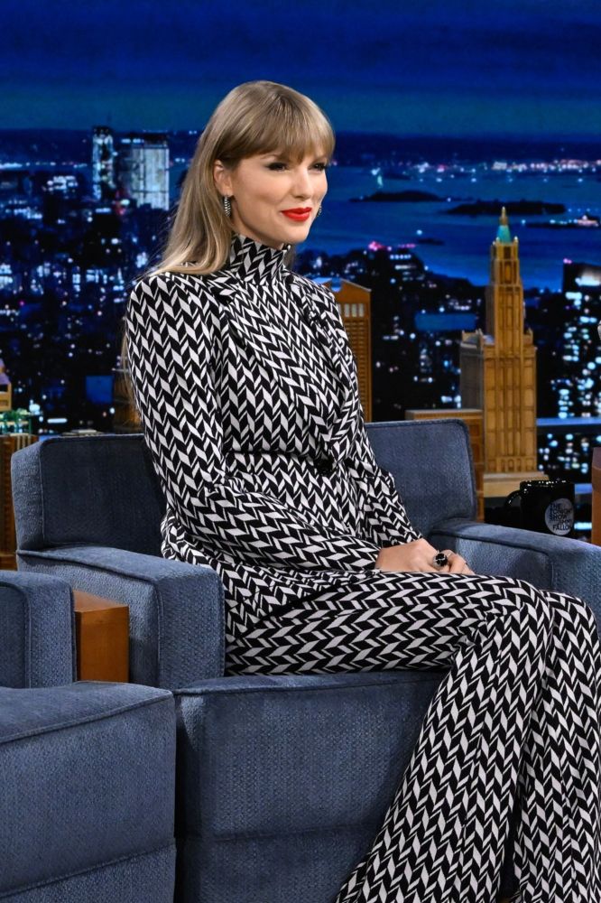 Taylor swift on The Tonight Show Starring Jimmy Fallon wearing black and white outfit, sitting on a blue chair.