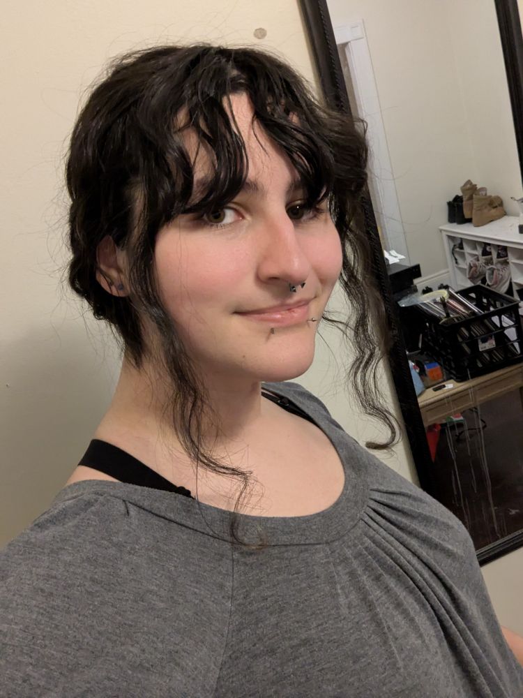 Me in a grey blouse with bra straps peeking on my shoulders. My hair's in a silly half up half down style
