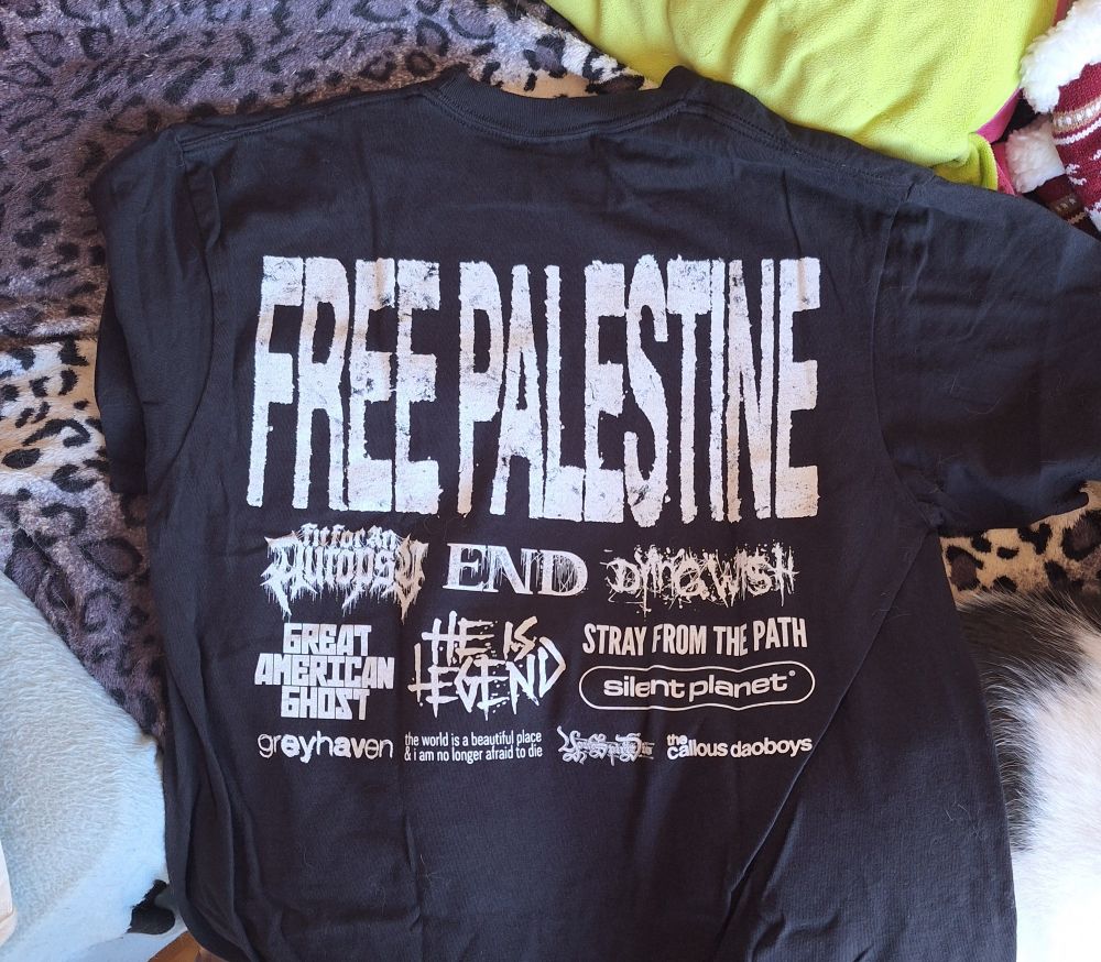 the backside of the same shirt that says "free palestine" in all caps
under it are names of multiple bands: fit for an autopsy, end, dying wish, greay american ghost, he is legend, stray from the path, silent planet, greyhaven, the world is a beautiful place & I am no longer afraid to die, your spirit dies and the callous daoboys
