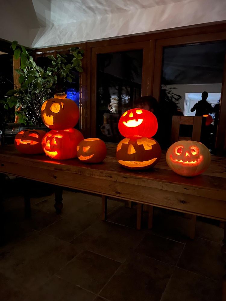7 pumpkins carved with various faces on a table