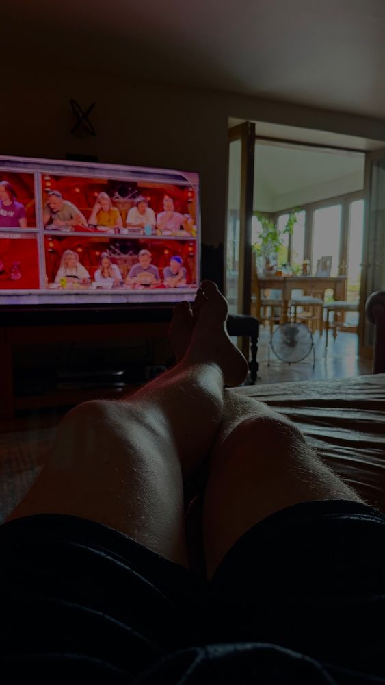 Picture of legs in a darkened room with Critical Role in the background. 