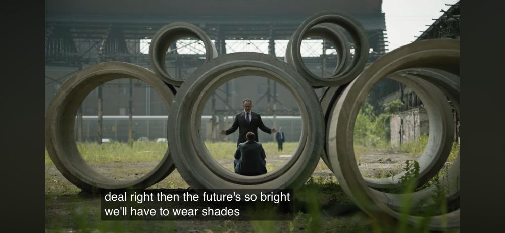 Screenshot from the television show Patriot. Beleaguered protagonist John is being inundated with bad news, including from his boss’s boss, Lawrence. Lawrence is glibly telling John that the company’s bankrupt, but he expects their fortunes will change after securing a major contract. While it’s clear to John and viewers that securing the contract is unlikely, Lawrence unconvincingly says “the future’s so bring we’ll have to wear shades.” 