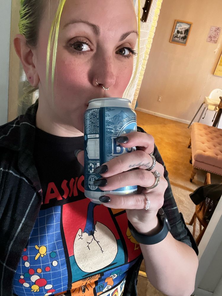 holding a busch light, showing off black, purple and blue shiny nails 