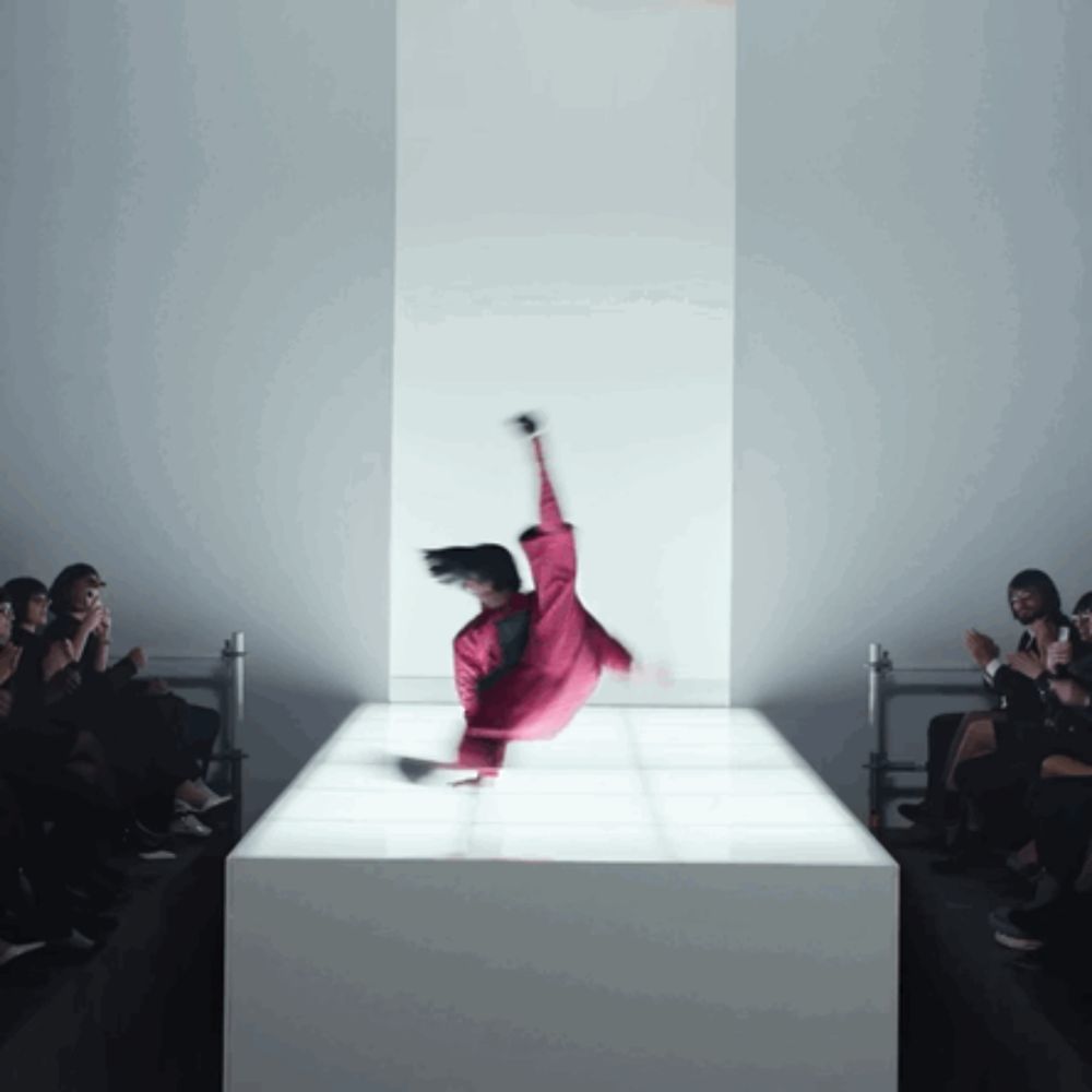 a woman in a red jumpsuit is doing a trick on a white podium