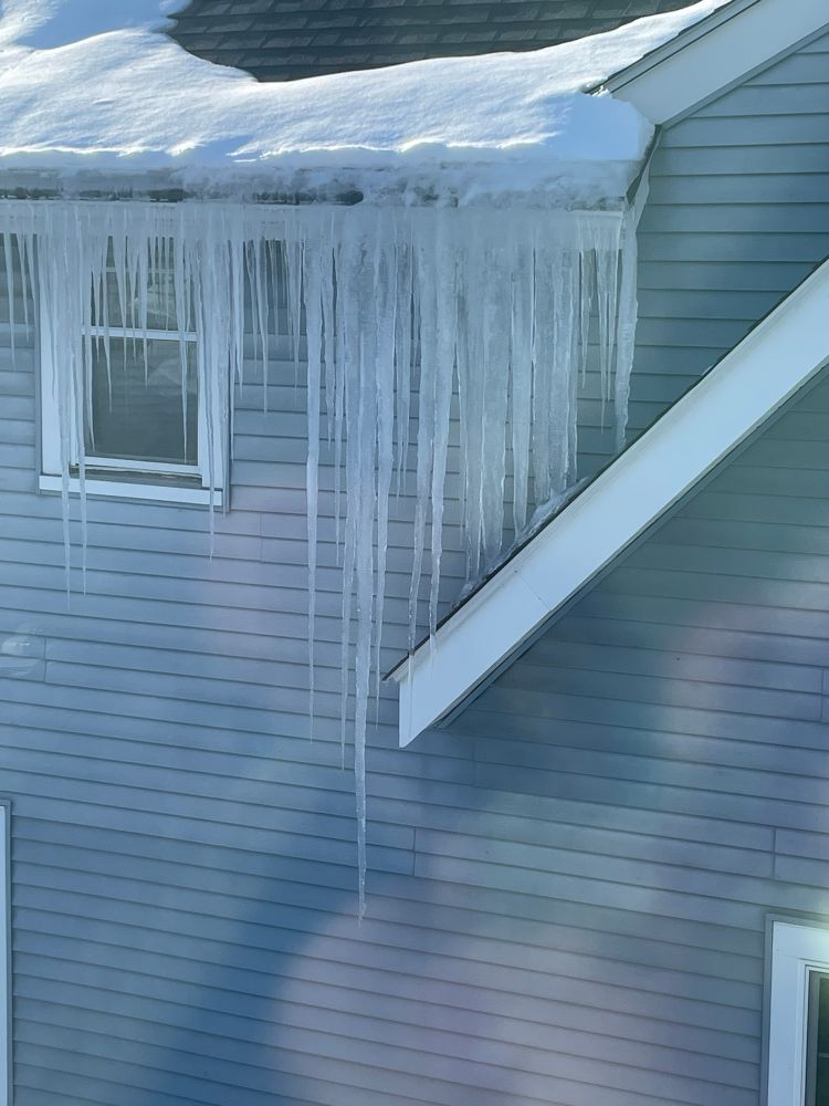 A side of a house with a large collection of icicles. The largest icicle is over one story in length. 
