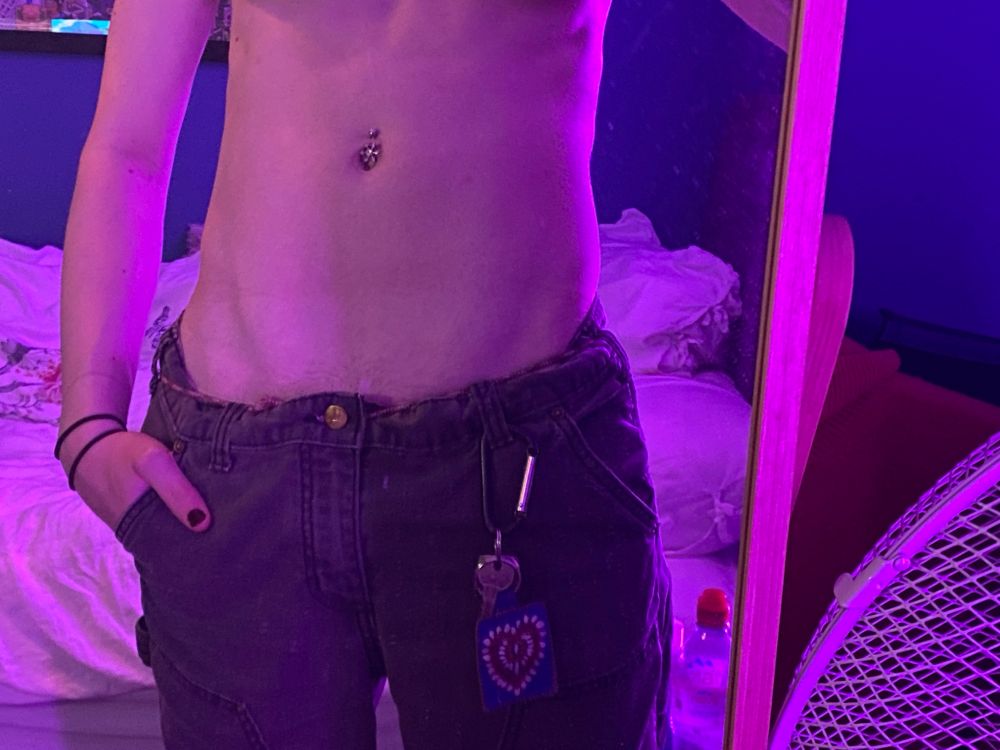 Another mirror selfie of June’s abdomen she is wearing trousers and her right hand is in her pocket she is also wearing a carabiner 