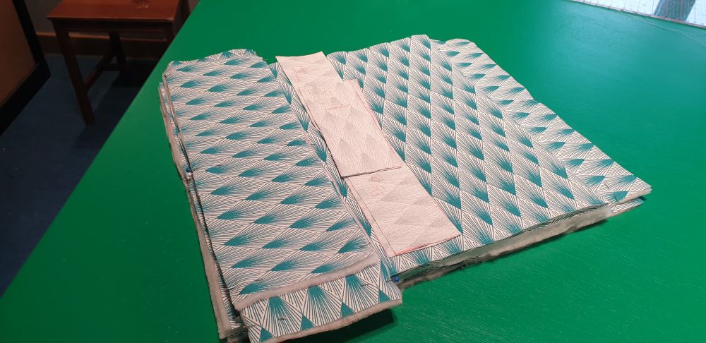 Photographie de carrés et rectangles de tissu, certains épinglés à du rembourrage. 