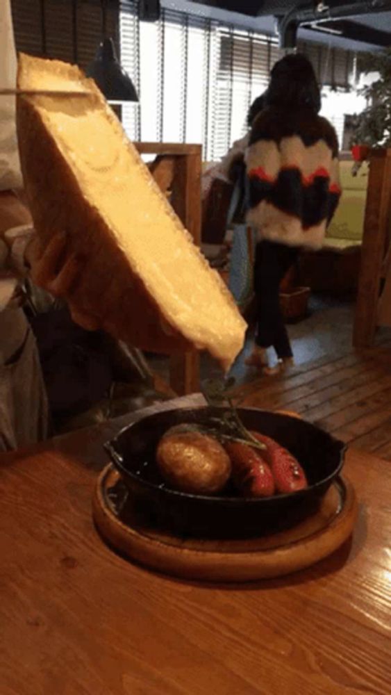 a person is holding a piece of cheese over a plate of food