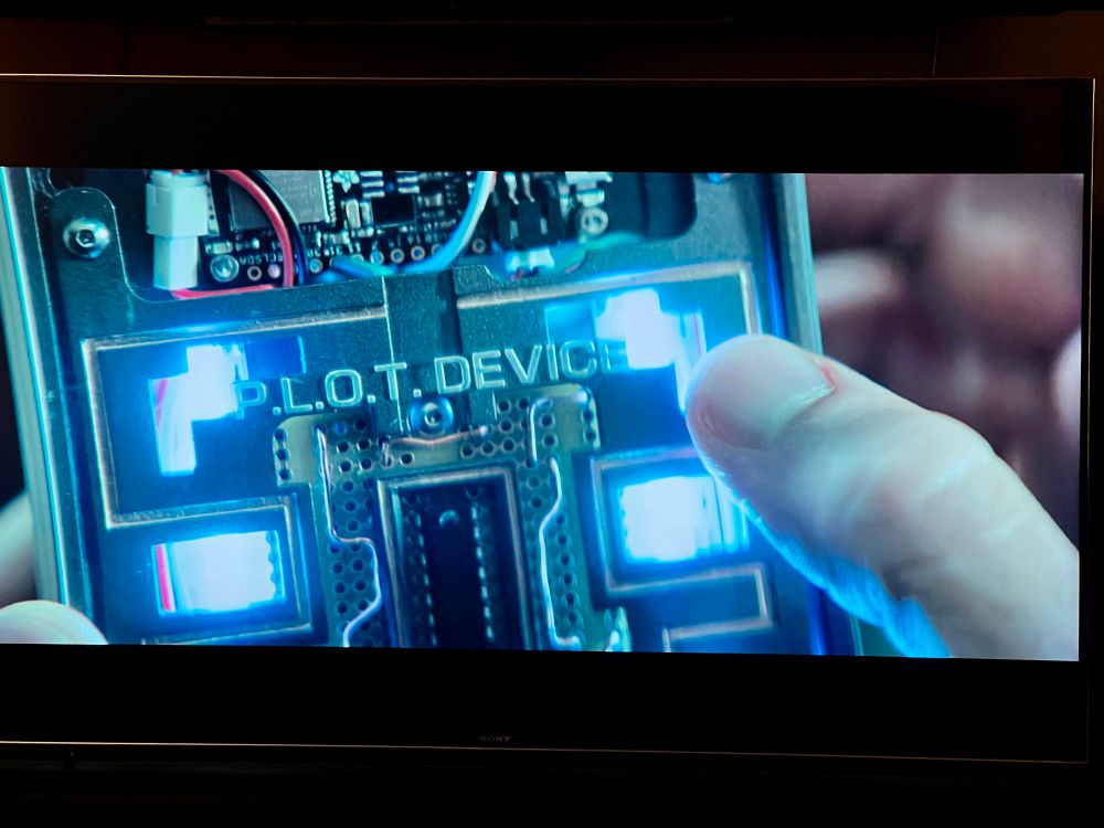 Opening scene of the new Naked Gun movie with a bad guy holding a device he’s stealing that says P.L.O.T DEVICE on it