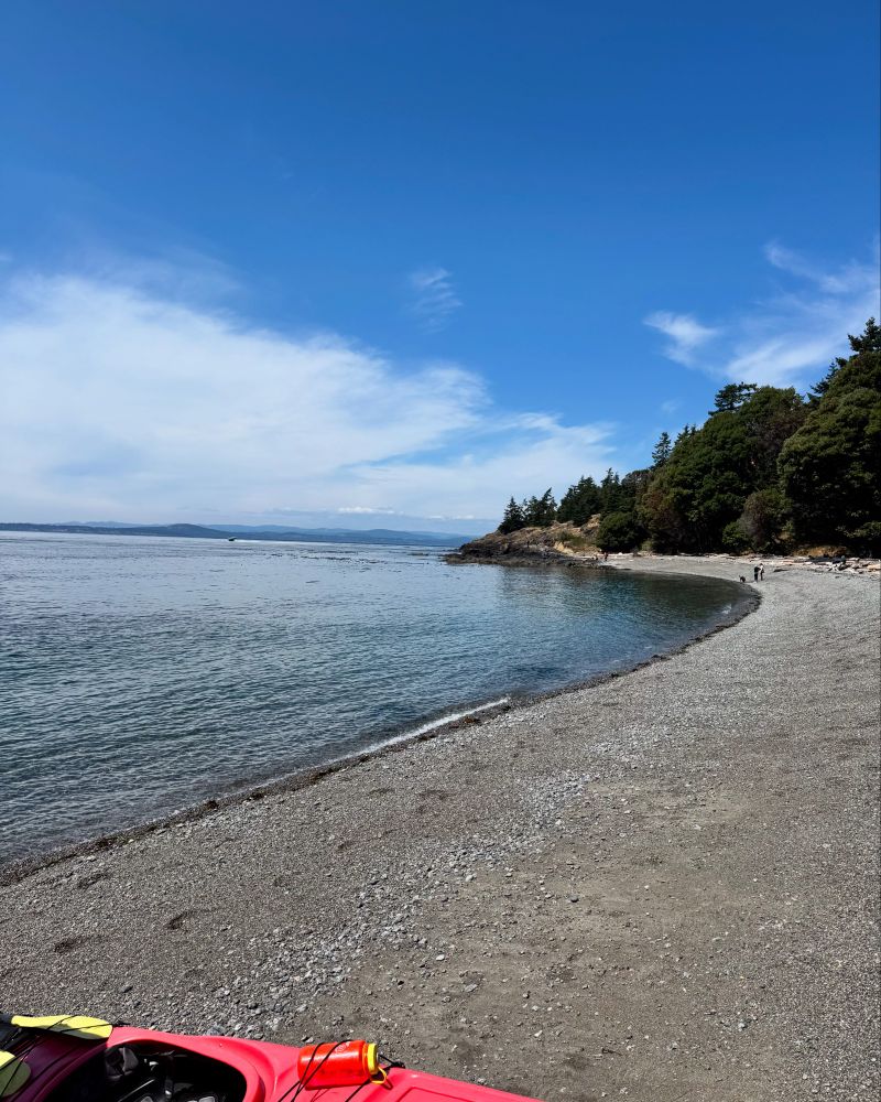 A long sand and pebble beach cove with blue sky overhead 
