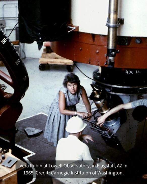 An adult Vera Rubin leans down beneath a large observatory telescope that extends up and out of frame.