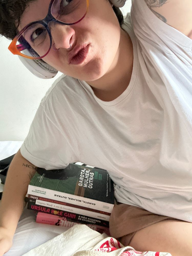 eu, uma garota branca de cabelos curtinhos e usando fones brancos, camisa branca e shortinho marrom estou “abraçada” nos livros que comprei hoje no sebo: “garota, mulher, outras” de bernardine evaristo, “laços” do domenico starnone, “a arte da brevidade” da virginia woolf, “a mão esquerda da escuridão” da ursula k le guin e “o que terá acontecido a baby jane?” do henry farrell