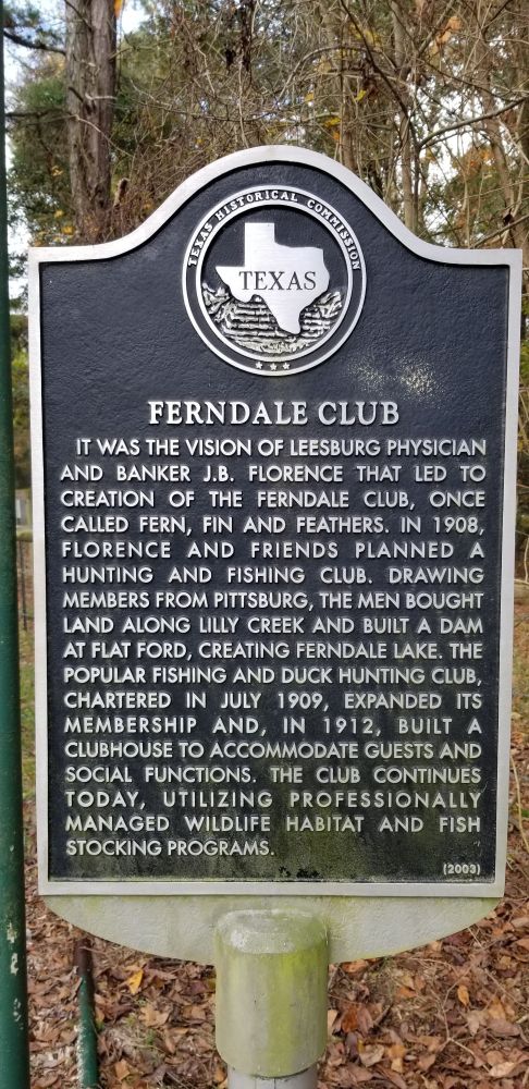Texas Historical Commission marker for Ferndale Club. 

Ferndale club. It was the vision of leeburg physician and banker J.B. Florence that led to the creation of Ferndale Club, once called Fern, Fin and Feathers. In 1908, Florence and friends planned a hunting and fishing club. Drawing members from Pittsburg, the men bought land along Lilly Creek and built a dam at Flat Ford, creating Ferndale Lake. The popular fishing and duck hunting club, chartered in July 1909, expanded its membership and, in 1912, built a clubhouse to accommodate guests and social functions. The club continues today, utilizing professionally managed wildlife habitat and fish stocking programs.