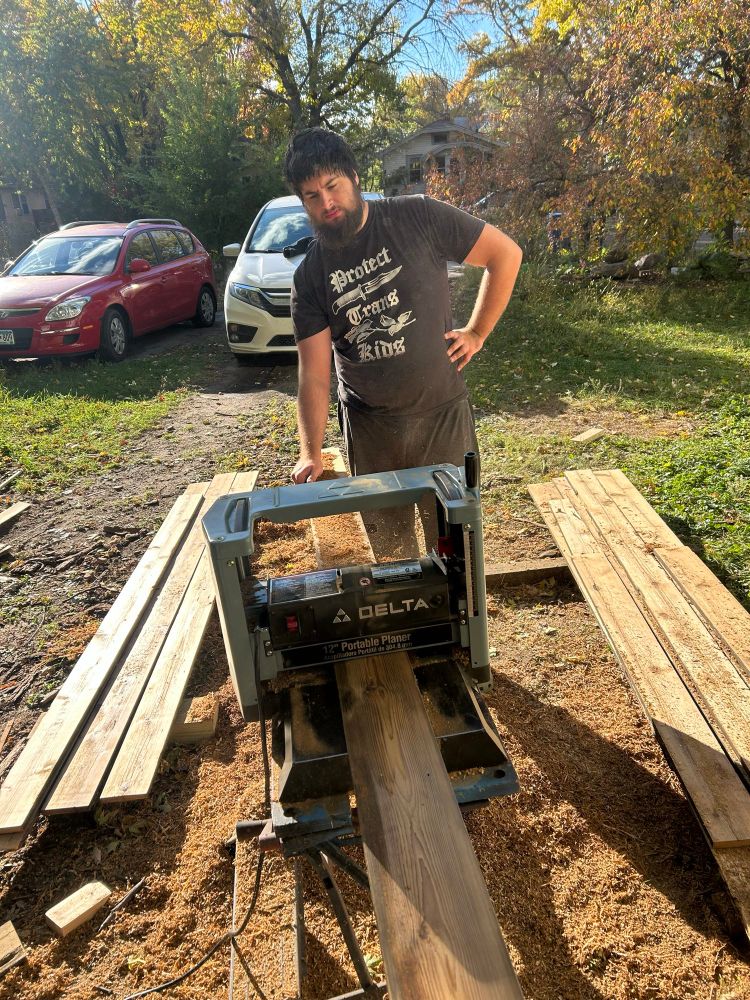 Riley catching a cedar board as it come out of a surface planer. 