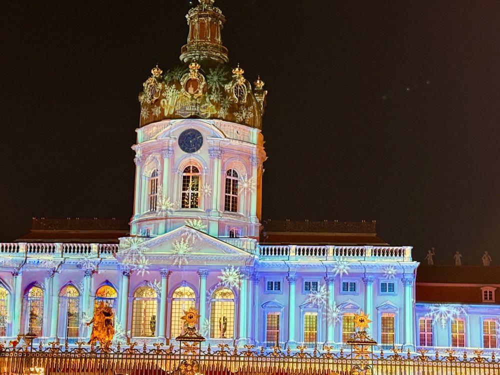 Foto von der Fassade des Schloss Charlottenburg, die illuminiert ist mit Schneeflocken. 